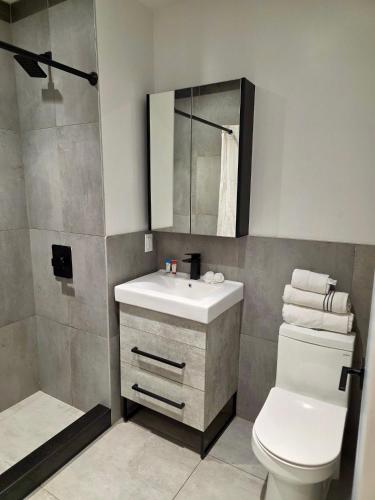 a bathroom with a sink and a toilet and a mirror at Rose Hotel Near Yankee Stadium in Bronx
