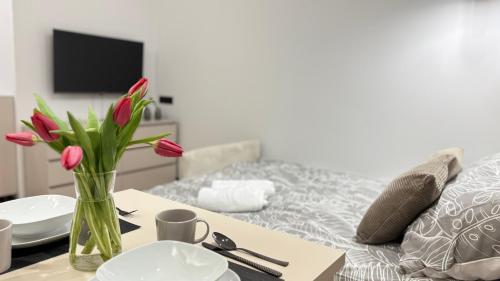 Eine Vase mit roten Tulpen auf einem Tisch neben einem Bett in der Unterkunft Studio 39 in Płock