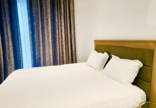 a bed with white sheets and pillows next to a window at 7th Heaven luxury Apartment in Gaborone