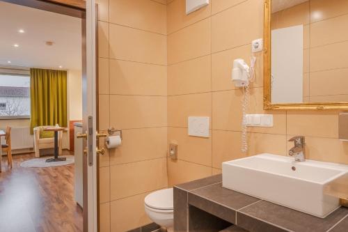 a bathroom with a sink and a toilet and a mirror at Hotel Victoria in Hochheim am Main