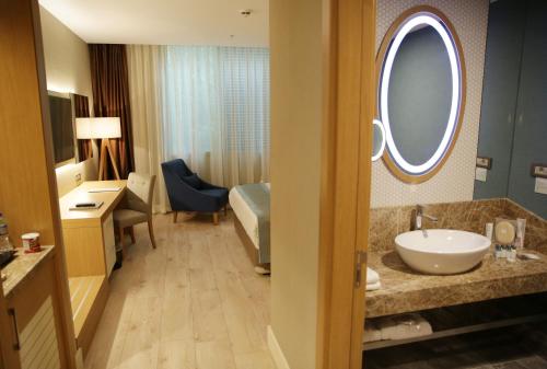 a bathroom with a sink and a bed and a mirror at The Ankara Hotel in Ankara