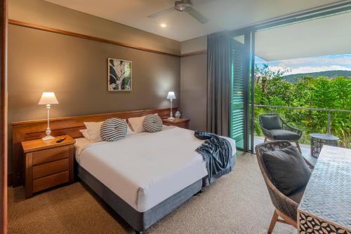a bedroom with a bed and a chair and a window at Yacht Club 33 Serenity House Ocean Views 2 Buggies in Hamilton Island