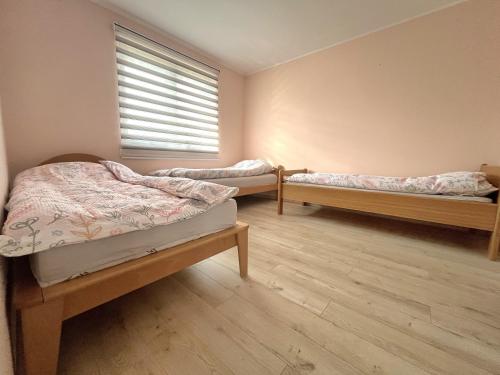 three beds in a room with a window and wooden floors at Pista house in Beograd