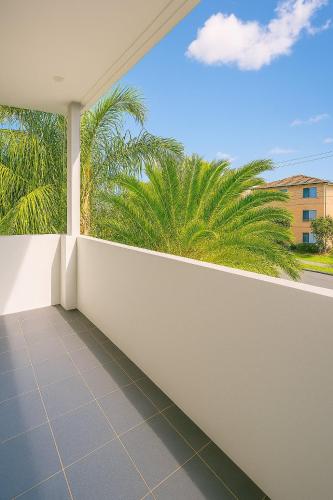 a balcony with a view of palm trees at New & Stylish Veg 2-Bedroom Guest Retreat Near Brisbane Airport in Brisbane