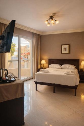 ein Schlafzimmer mit einem Bett und einem Fernseher in der Unterkunft Saint John Hotel in Madaba