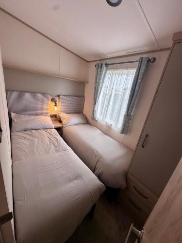 two beds in a small room with a window at Blue dolphin static in Gristhorpe