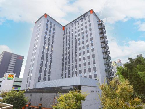 a tall white hotel building in a city at APA Hotel Keisei Narita Ekimae in Narita