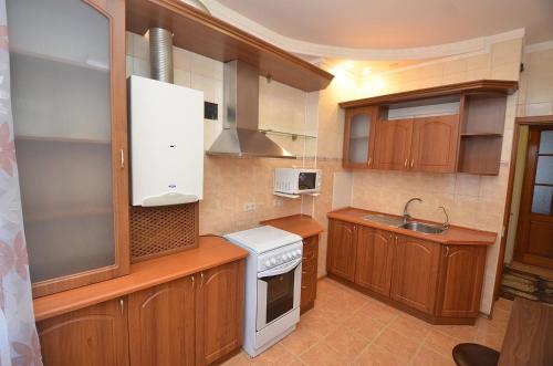 a kitchen with wooden cabinets and a white stove top oven at Apartment in the center on Spasskaya Street in Mykolaiv