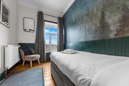 a bedroom with a bed and a chair and a window at Stunning Townhouse - 7 bedrooms - up to 18 Guests in Cardiff