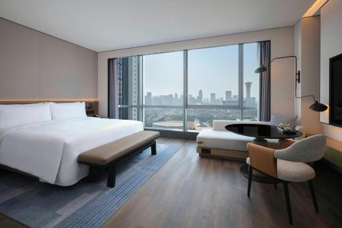 a bedroom with a bed and a desk and a large window at Sheraton Ningbo Yinzhou in Ningbo