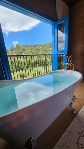 a bath tub in a room with a large window at Chalés Monte das Oliveiras in Domingos Martins