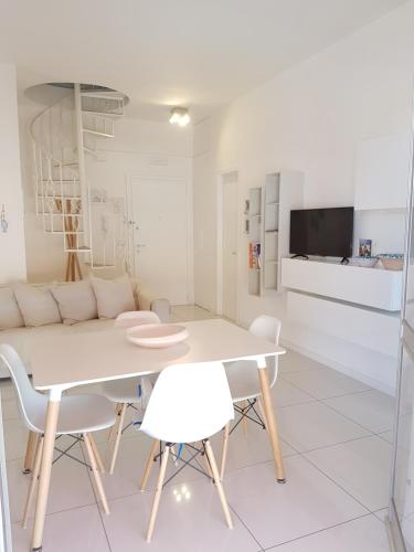 ein weißes Esszimmer mit einem weißen Tisch und Stühlen in der Unterkunft La Casa Bianca in Ceriale