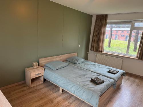 a bedroom with a bed with blue sheets and a window at Boslust in Bergen op Zoom
