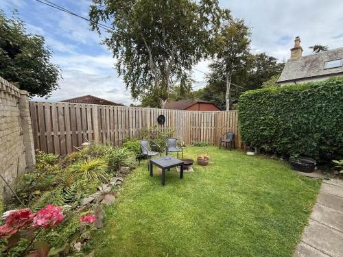a backyard with a table and chairs and a fence at Robins Nest Cottage in Blairgowrie