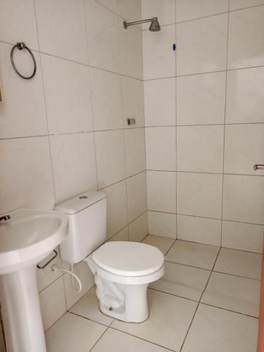 a white bathroom with a toilet and a sink at Casa mobiliada 2 Com 4 camas e 2 quartos com ar condicionado in Juazeiro do Norte