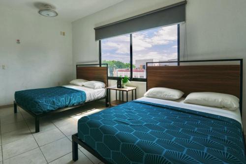 a bedroom with two beds and a large window at Casa Zapopan Hotel in Guadalajara