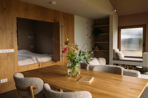 a room with a wooden table with a vase of flowers on it at Gastenverblijf Buitenhoudt in Vinkel