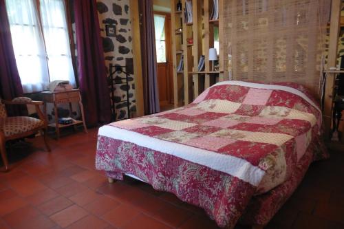 a bedroom with a bed with a red and white quilt at la Loge à SANSSAC in Sanssac-lʼÉglise