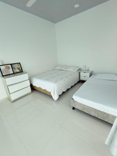two beds in a bedroom with white walls at Casa WHITE in Melgar
