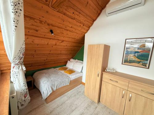 a small bedroom with a bed and a wooden ceiling at Łykolańczyk-Chatki z JACUZZI in Polańczyk