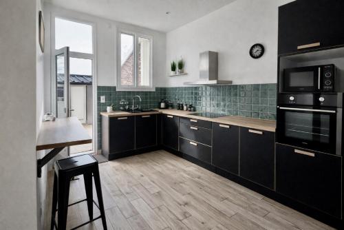 a kitchen with black cabinets and a counter top at La Coloc Boho - Saint-Quentin, chambres centre, idéal pro in Saint-Quentin
