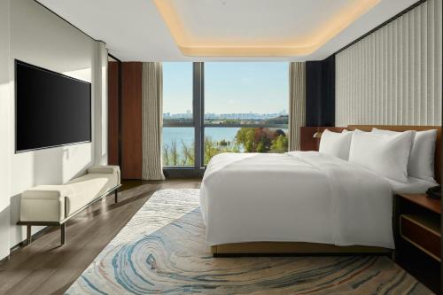 a bedroom with a large white bed and a large window at Sheraton Suzhou Yangcheng Lake in Suzhou