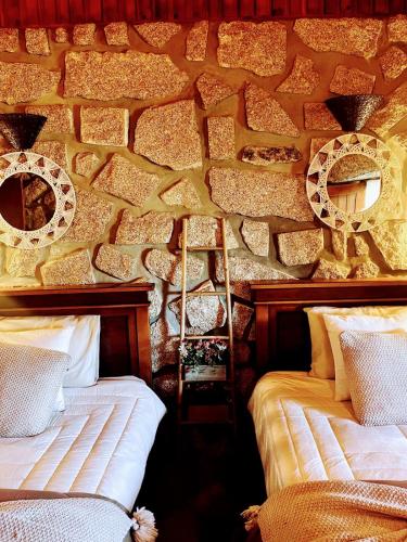 a room with two beds and a stone wall at Casa do Monte Sereno in Celorico de Basto