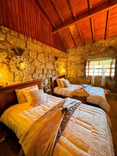 a bedroom with two beds and a stone wall at Casa do Monte Sereno in Celorico de Basto