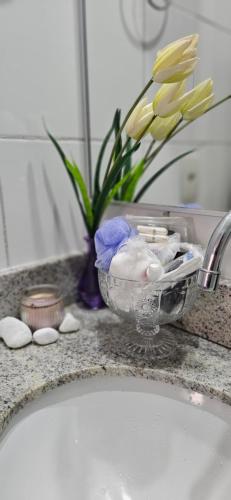 a bathroom counter with a sink and a vase with flowers at Apê Panoramic Águas Claras e Ministérios in Brasília