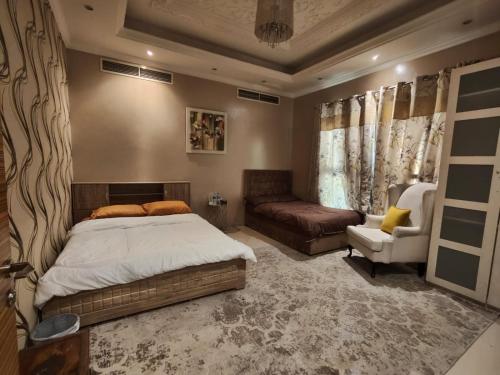 a bedroom with a bed and a couch and a chair at Huge luxury villa stay with private room in Ajman