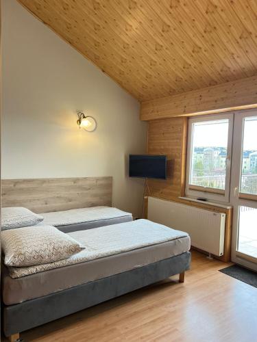 a bedroom with two beds and a flat screen tv at Bursztynowy Brzeg in Sarbinowo
