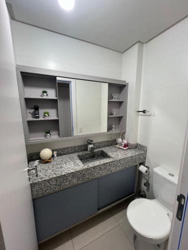 a bathroom with a sink and a toilet and a mirror at Lindo apartamento todo equipado in Criciúma