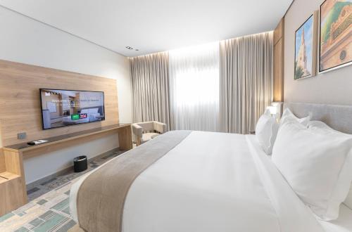 a hotel room with a large bed and a flat screen tv at فندق آفال AVAL Hotel in Medina