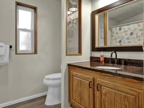a bathroom with a toilet and a sink and a mirror at Beach Bum Cabin in Florence