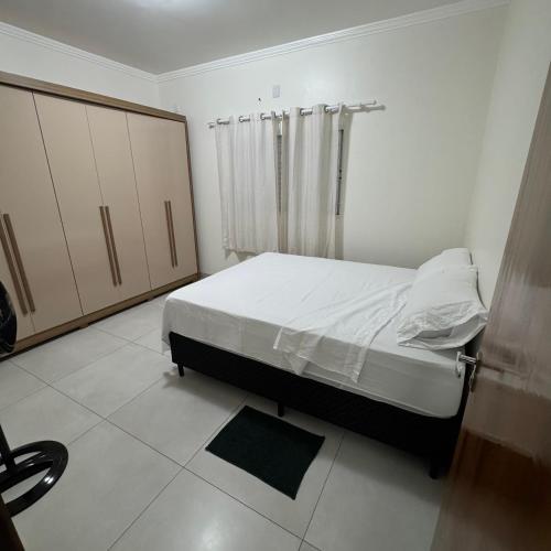 a white bedroom with a bed and a window at Apto Cozi in Sorriso