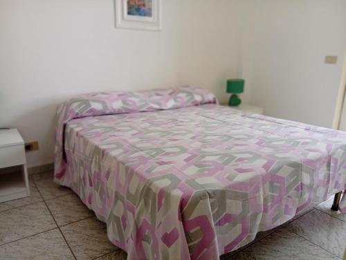 a bedroom with a bed with a pink and gray comforter at Casa Torre in Fiumefreddo Bruzio