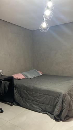 a bed in a room with a light hanging from the ceiling at jaó, mazzahome in Goiânia