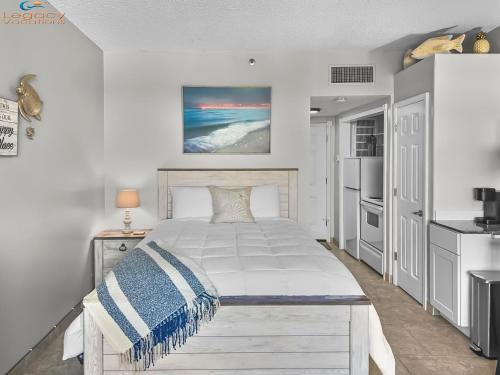 a bedroom with a white bed with a blue and white blanket at Pirates Bay B303 in Fort Walton Beach