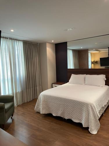 a bedroom with a large white bed and a chair at Sequoia - Alphaville in Barueri