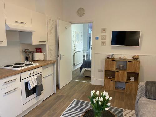 a small kitchen with a stove and a living room at Harbour House Holiday Apartments in Bridlington