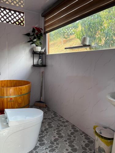 a bathroom with a toilet and a sink and a window at Căn gentle home in Da Lat
