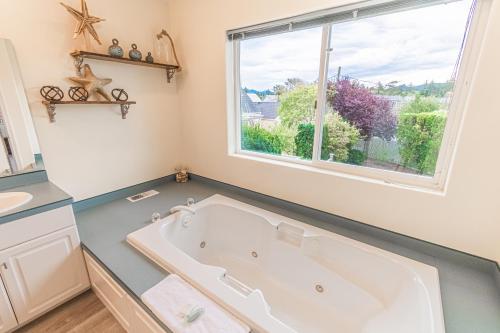 a bath tub in a bathroom with a window at Sand On My Toes in Seaside