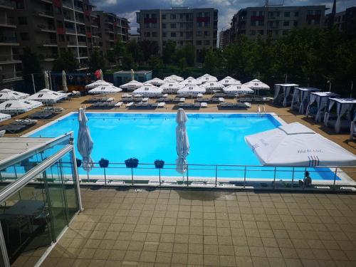 a large blue swimming pool with umbrellas and chairs at Alex MNL lux Apartment 2 free parking in Bucharest