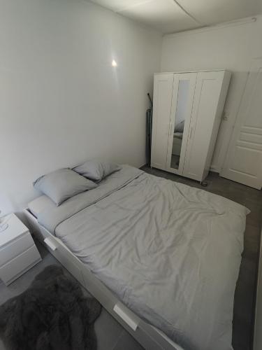 biały pokój z łóżkiem i lustrem w obiekcie Le Fabre w Besançon