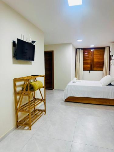 a bedroom with a bed and a tv on a wall at Bigorú Flats in Itacaré