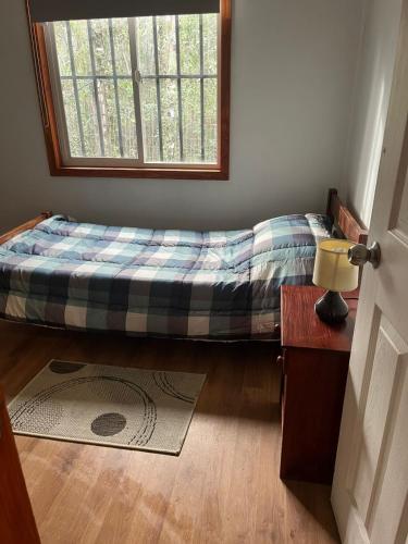 a bed sitting in a room with a window at Casa familiar en parcela privada Pucón in Pucón