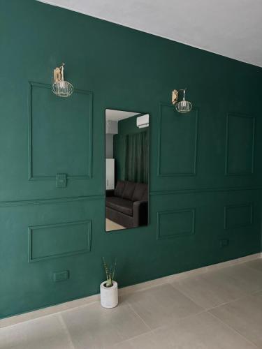 a green room with a couch and a mirror at Tandem - Espacio para dos - Cama King - Parking in Maipú