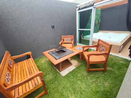 a patio with two benches and a table and chairs at Refugio Vem Viver in Mairiporã