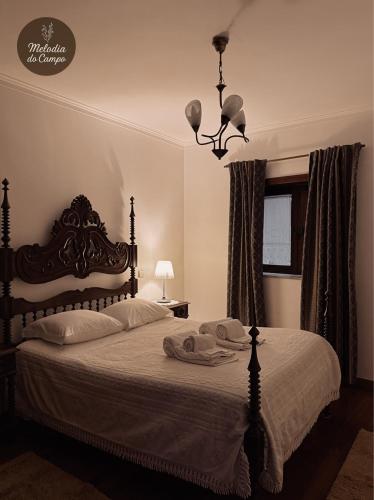 a bedroom with a bed and a chandelier at Melodia do Campo in Terras de Bouro