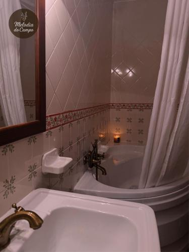 a bathroom with a tub and a sink and a mirror at Melodia do Campo in Terras de Bouro